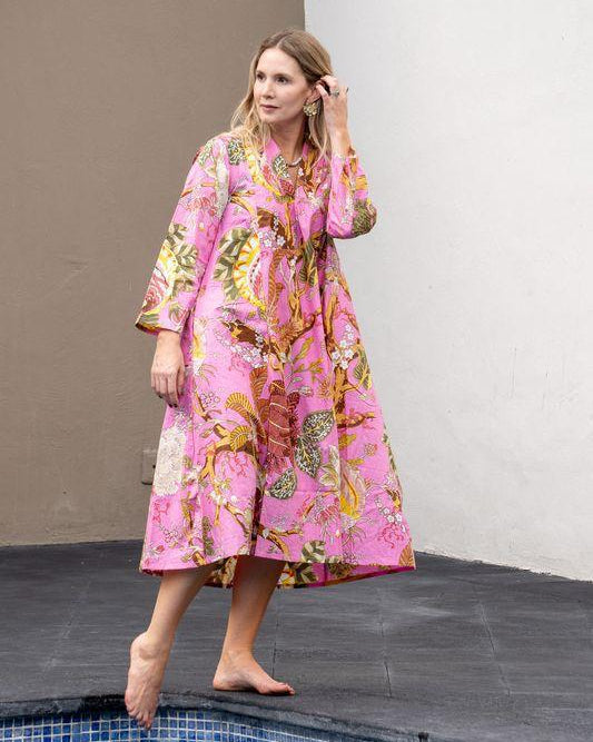 Woman in a pink floral dress standing by a pool.