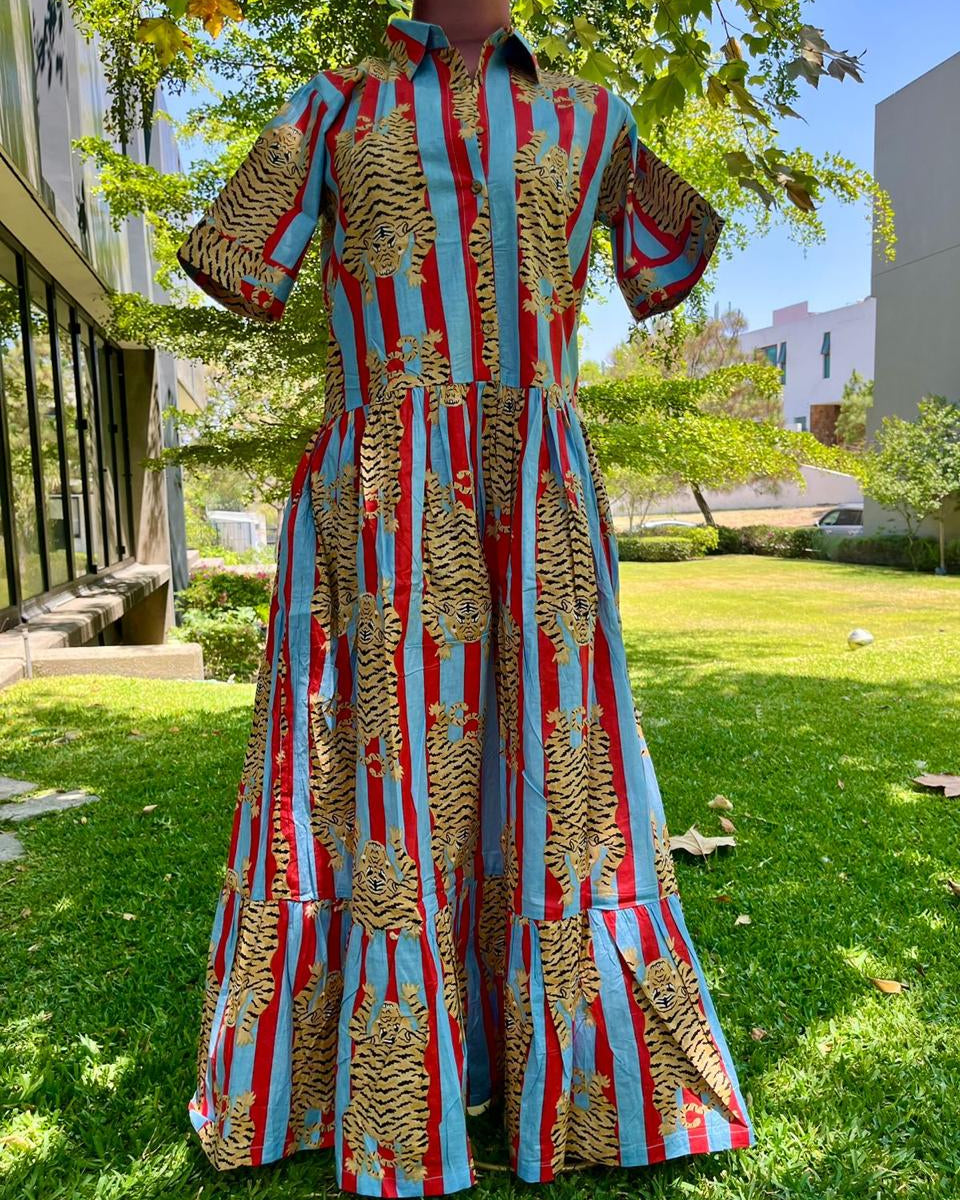 Mannequin wearing a colorful dress with red, blue, and gold patterns on grass.